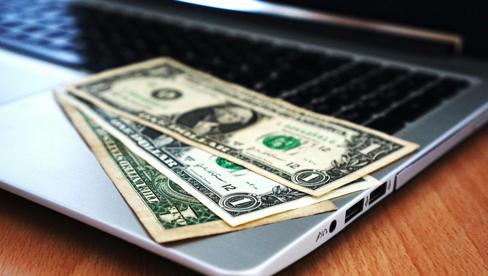 Close-up of US dollar bills placed on a laptop symbolizing digital finance and economy.