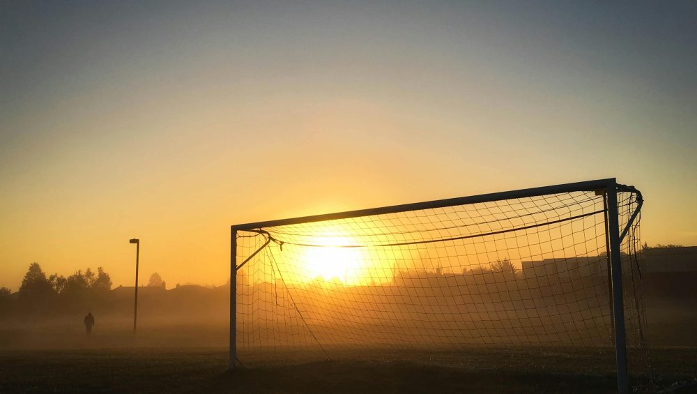 Soccer goal silhouetted against a misty sunrise in a tranquil Mississauga field.
