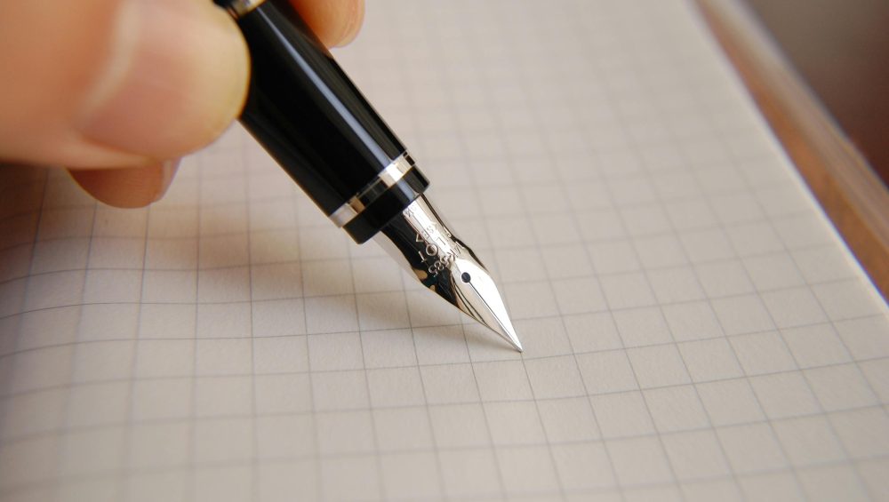 A detailed close-up of a fountain pen poised over graph paper, ideal for educational or business use.