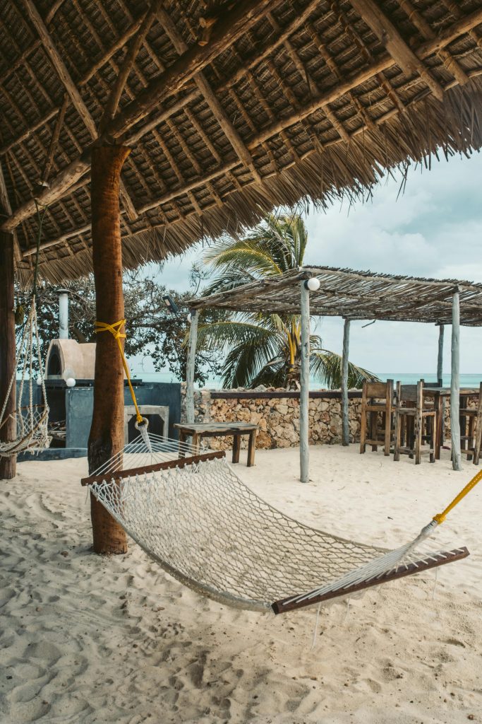 Relax in a hammock under palm leaves on a Zanzibar beach, perfect for a tropical vacation.
