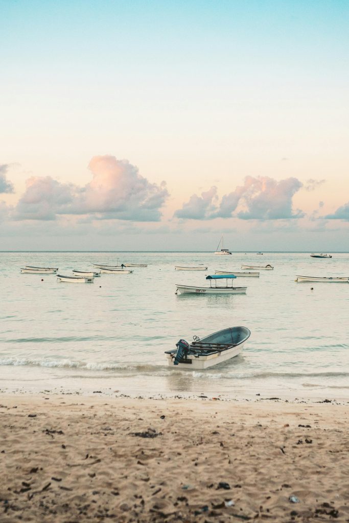 Tranquil view of boats anchored near the shore of Zanzibar against a serene sunset sky.