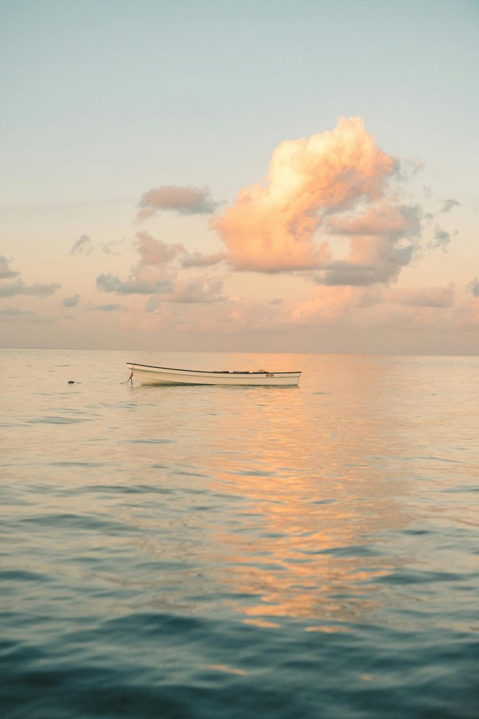 Peaceful sunset view over the calm Zanzibar waters featuring a lone boat and dramatic clouds.