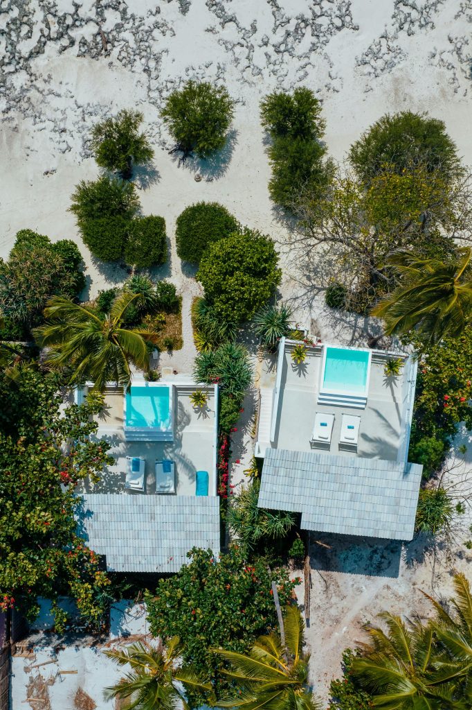 Top-down view of luxury beachfront villas with private pools and lush greenery in Zanzibar.