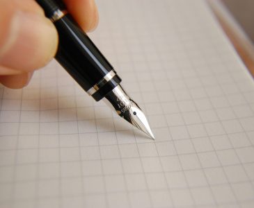 A detailed close-up of a fountain pen poised over graph paper, ideal for educational or business use.